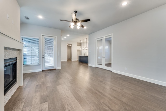 8532 Melrose, The Colony, TX 75056 - unfurnished living room featuring a glass covered fireplace, a ceiling fan, french doors, dark wood-style floors, and recessed lighting