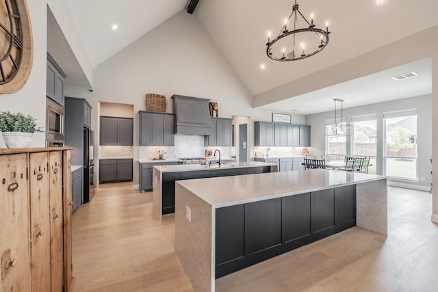 562 Broadleaf Way, Haslet, TX 76052 - kitchen with a large island with sink, a chandelier, light wood-style floors, high vaulted ceiling, and stainless steel microwave