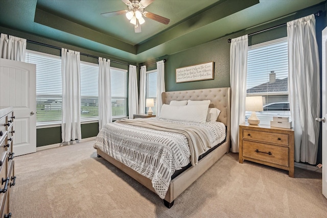 168 Ridgetop Trl, Rhome, TX 76078 - bedroom with light carpet, a tray ceiling, and a ceiling fan