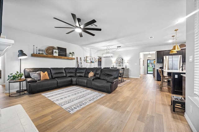 168 Ridgetop Trl, Rhome, TX 76078 - living room with a ceiling fan, light wood-style flooring, baseboards, and a chandelier