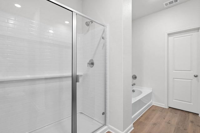 426 Gib Woodall Dr, Venus, TX 76084 - bathroom featuring wood finished floors, a stall shower, a bath, baseboards, and recessed lighting