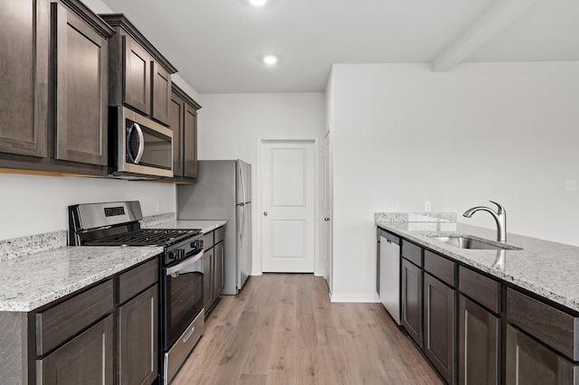426 Gib Woodall Dr, Venus, TX 76084 - kitchen featuring appliances with stainless steel finishes, a sink, dark brown cabinetry, light wood-style floors, and light stone countertops