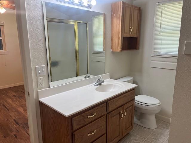 214 Hemphill St, Hico, TX 76457 - full bathroom with vanity, toilet, a stall shower, and baseboards