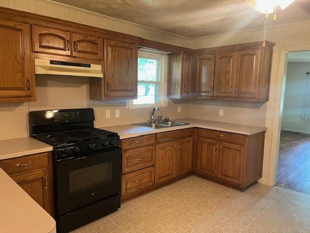 214 Hemphill St, Hico, TX 76457 - kitchen with black range with gas cooktop, under cabinet range hood, a sink, light countertops, and ornamental molding
