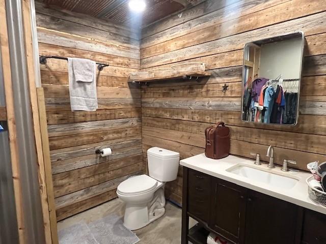 214 Hemphill St, Hico, TX 76457 - half bath with wood walls, vanity, toilet, and concrete floors