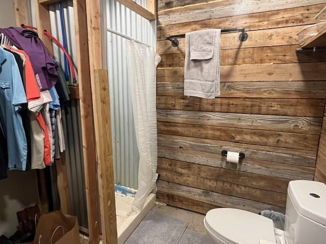 214 Hemphill St, Hico, TX 76457 - bathroom with wooden walls, toilet, and a shower with curtain