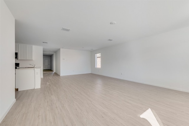 2037 Welsh Ln, Aubrey, TX 76227 - unfurnished living room with light wood-style flooring, a sink, and baseboards