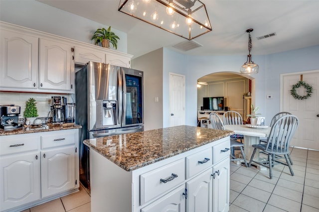 3820 Blossom Dr, Sachse, TX 75048 - kitchen featuring arched walkways, light tile patterned flooring, white cabinetry, dark stone countertops, and a center island