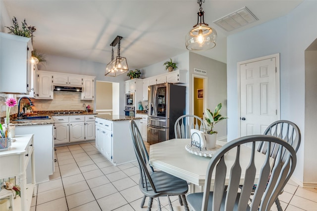 3820 Blossom Dr, Sachse, TX 75048 - kitchen featuring stainless steel appliances, a sink, light tile patterned floors, white cabinetry, and a kitchen island