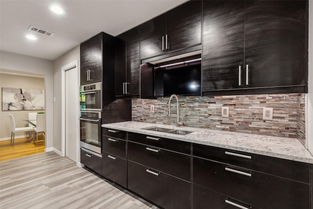 9705 Ash Creek Dr, Dallas, TX 75228 - kitchen with a sink, light wood-style flooring, tasteful backsplash, stainless steel double oven, and recessed lighting