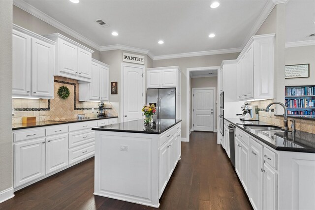 41 N Shore Cir, Waco, TX 76708 - kitchen with stainless steel appliances, a sink, dark countertops, white cabinetry, and ornamental molding
