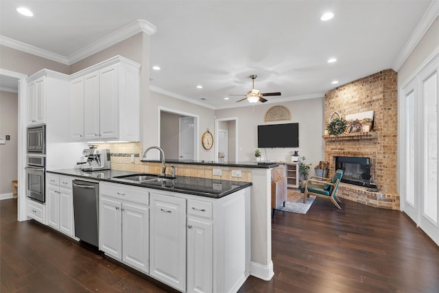 41 N Shore Cir, Waco, TX 76708 - kitchen featuring a sink, stainless steel appliances, dark countertops, ceiling fan, and a fireplace
