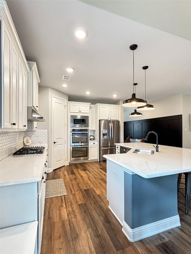2219 Wellington Ln, Corinth, TX 76210 - kitchen featuring appliances with stainless steel finishes, a sink, dark wood finished floors, white cabinets, and tasteful backsplash