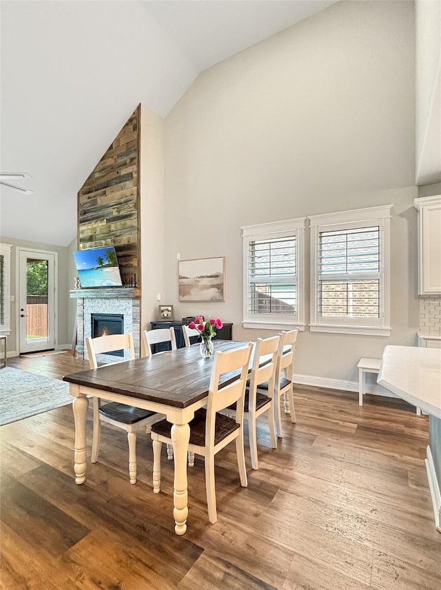 2219 Wellington Ln, Corinth, TX 76210 - dining area with high vaulted ceiling, a fireplace, light wood-style flooring, baseboards, and a ceiling fan