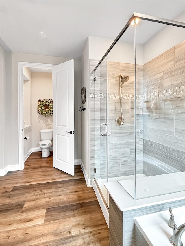 2219 Wellington Ln, Corinth, TX 76210 - bathroom with a stall shower, toilet, wood finished floors, and baseboards