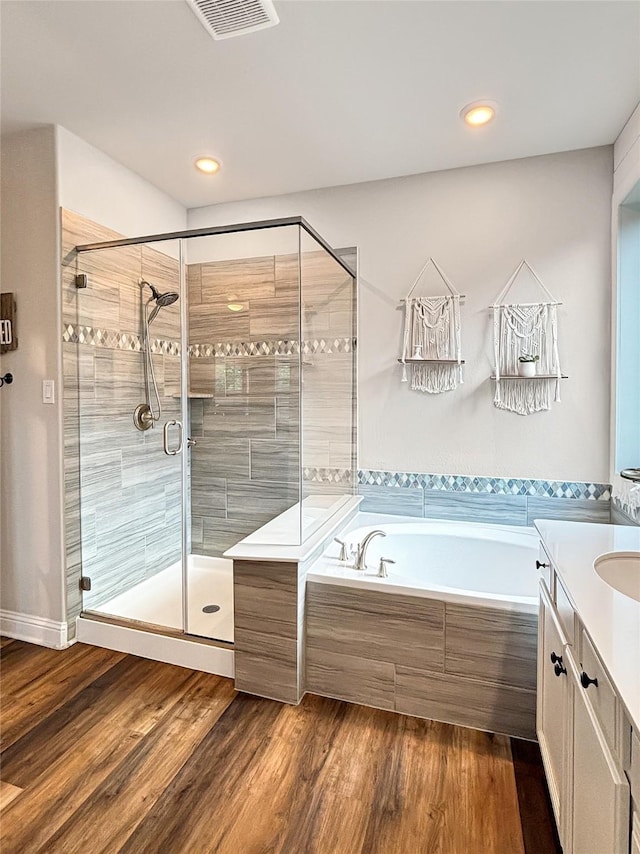 2219 Wellington Ln, Corinth, TX 76210 - bathroom with a bath, a stall shower, vanity, wood finished floors, and recessed lighting