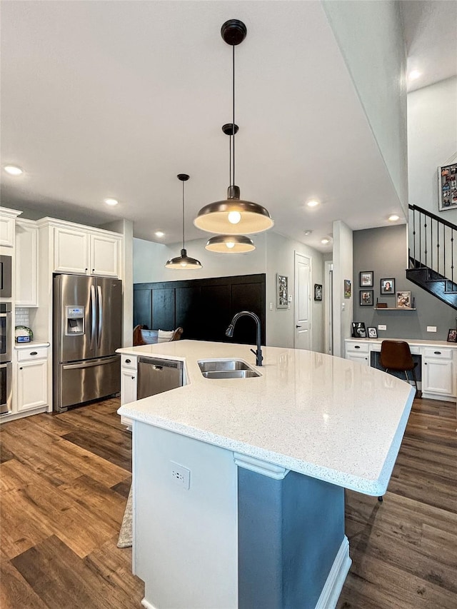 2219 Wellington Ln, Corinth, TX 76210 - kitchen with stainless steel appliances, a sink, dark wood-style floors, a large island with sink, and white cabinets