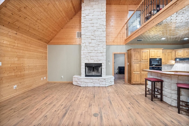 108 Fcr 868, Teague, TX 75860 - living room with high vaulted ceiling, wooden walls, a stone fireplace, light wood finished floors, and wooden ceiling
