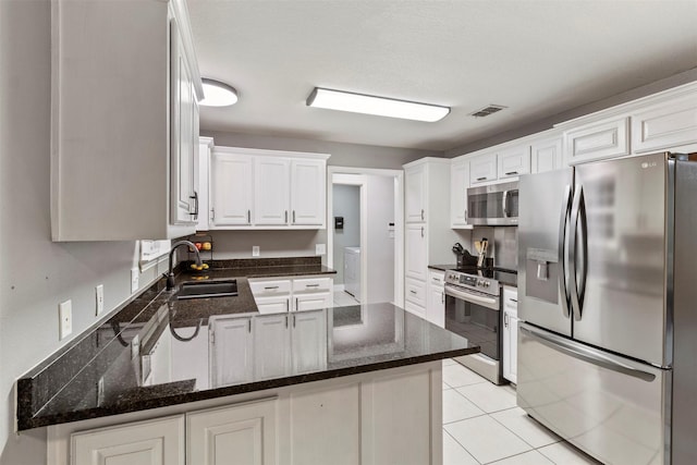 110 Harmon Cir, Blue Ridge, TX 75424 - kitchen featuring stainless steel appliances, a sink, independent washer and dryer, a peninsula, and white cabinetry