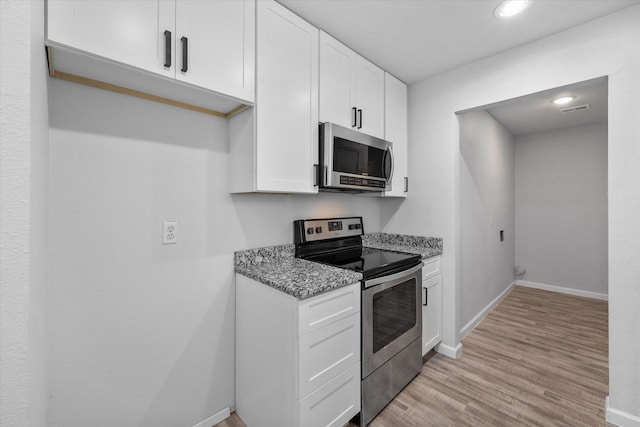 1312 E Collin, Corsicana, TX 75110 - kitchen featuring appliances with stainless steel finishes, white cabinetry, light stone counters, light wood-style floors, and baseboards