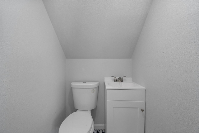 1312 E Collin, Corsicana, TX 75110 - bathroom featuring lofted ceiling, toilet, vanity, and a textured wall