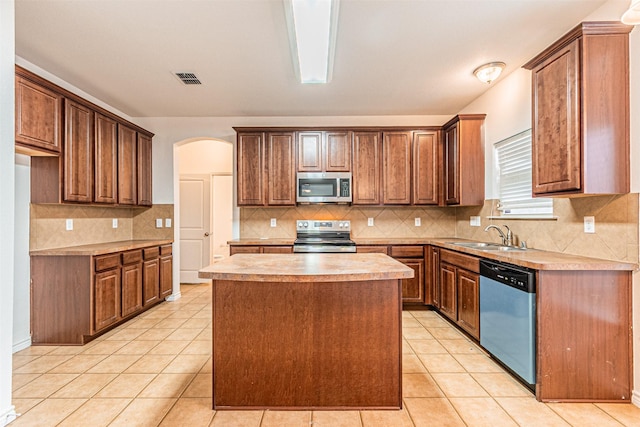 6547 Portside Ridge Ln, Dallas, TX 75249 - kitchen featuring appliances with stainless steel finishes, a sink, arched walkways, light countertops, and decorative backsplash