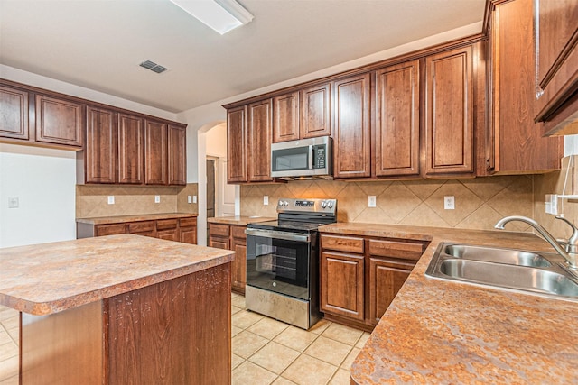 6547 Portside Ridge Ln, Dallas, TX 75249 - kitchen with stainless steel appliances, a sink, light countertops, light tile patterned floors, and tasteful backsplash