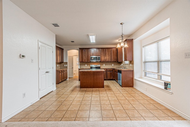 6547 Portside Ridge Ln, Dallas, TX 75249 - kitchen featuring stainless steel appliances, a center island, a sink, tasteful backsplash, and arched walkways