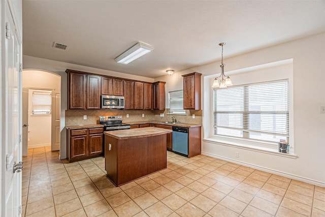 6547 Portside Ridge Ln, Dallas, TX 75249 - kitchen featuring stainless steel appliances, tasteful backsplash, a kitchen island, light countertops, and light tile patterned flooring