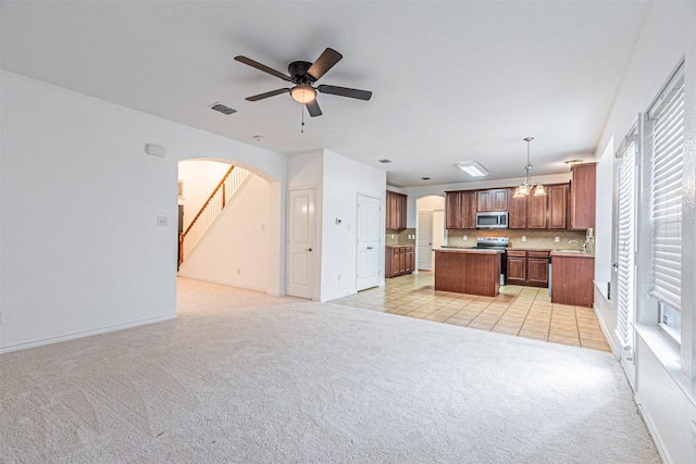 6547 Portside Ridge Ln, Dallas, TX 75249 - kitchen featuring appliances with stainless steel finishes, light colored carpet, a center island, open floor plan, and arched walkways