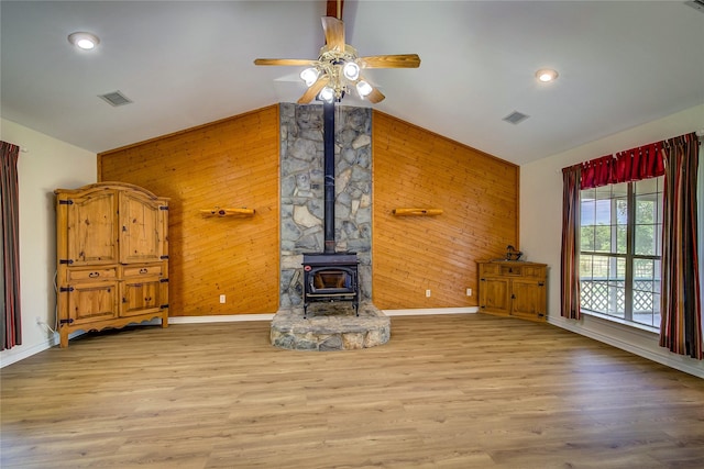 5701 Fm 2101, Quinlan, TX 75474 - unfurnished living room featuring vaulted ceiling, wood walls, baseboards, a wood stove, and a ceiling fan