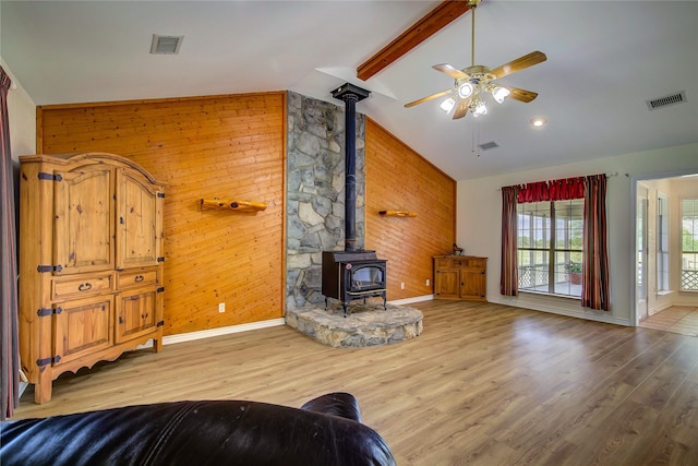 5701 Fm 2101, Quinlan, TX 75474 - living area with a wood stove, a ceiling fan, baseboards, wood walls, and light wood-style floors