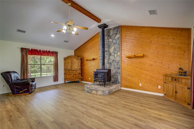 5701 Fm 2101, Quinlan, TX 75474 - living room with a wood stove, wood walls, a ceiling fan, baseboards, and wood finished floors