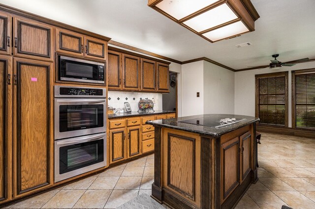 3313 Conlin Dr, Rowlett, TX 75088 - kitchen featuring appliances with stainless steel finishes, a center island, light tile patterned floors, dark stone counters, and ornamental molding
