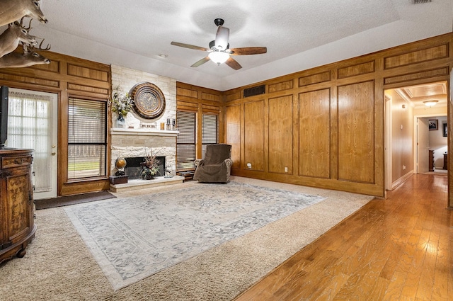 3313 Conlin Dr, Rowlett, TX 75088 - living area with ceiling fan, a textured ceiling, a fireplace, hardwood / wood-style floors, and wooden walls