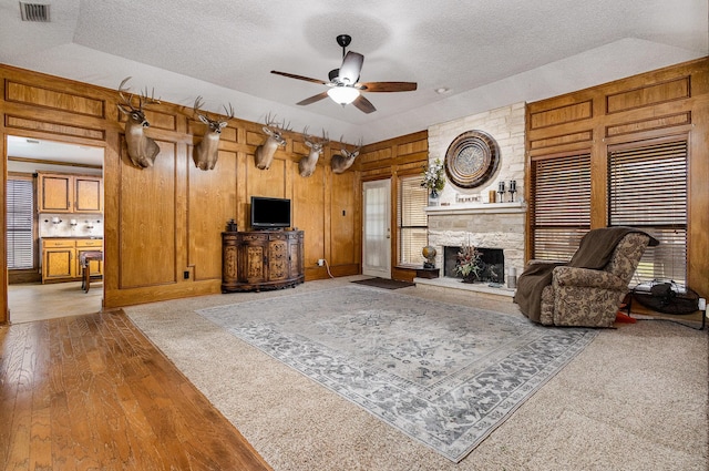 3313 Conlin Dr, Rowlett, TX 75088 - living room with a textured ceiling, ceiling fan, a fireplace, wood walls, and wood finished floors