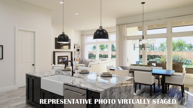 990 Stargrass Dr, Allen, TX 75013 - kitchen with a sink, light wood-type flooring, light stone counters, a glass covered fireplace, and pendant lighting