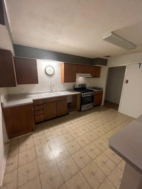 1231 Ravina Dr, Garland, TX 75041 - kitchen featuring gas stove, a sink, light countertops, and under cabinet range hood