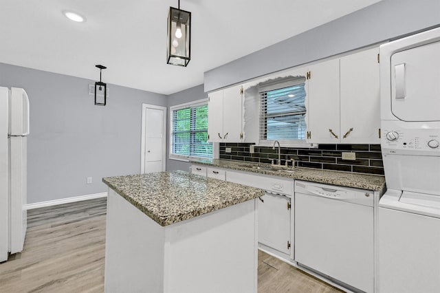 110 W Moore St, Sherman, TX 75090 - kitchen featuring stacked washer / dryer, white appliances, a sink, light wood finished floors, and white cabinets