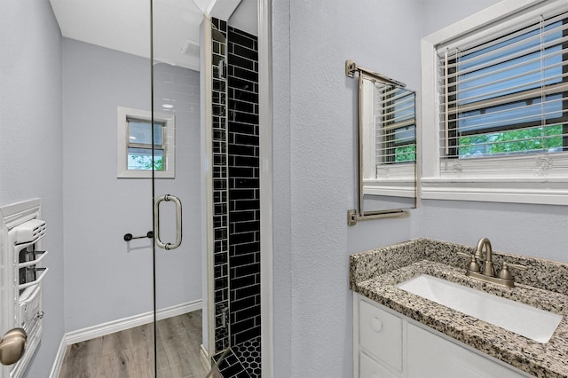 110 W Moore St, Sherman, TX 75090 - bathroom featuring wood finished floors, a stall shower, vanity, baseboards, and a textured wall