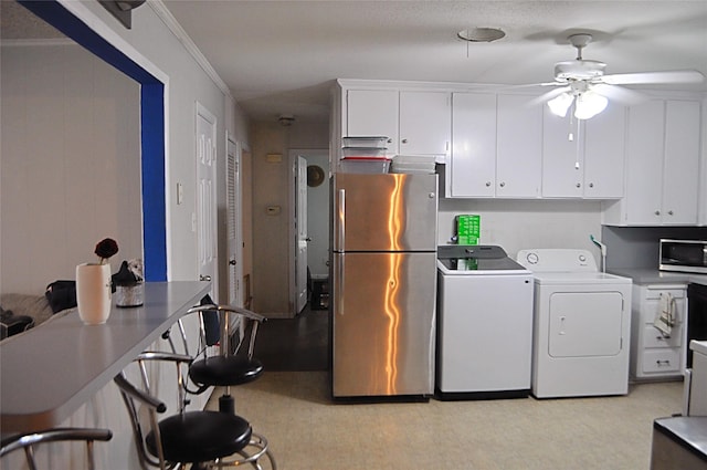 5328 Ira St N, Haltom City, TX 76117 - kitchen featuring appliances with stainless steel finishes, independent washer and dryer, ceiling fan, white cabinetry, and crown molding