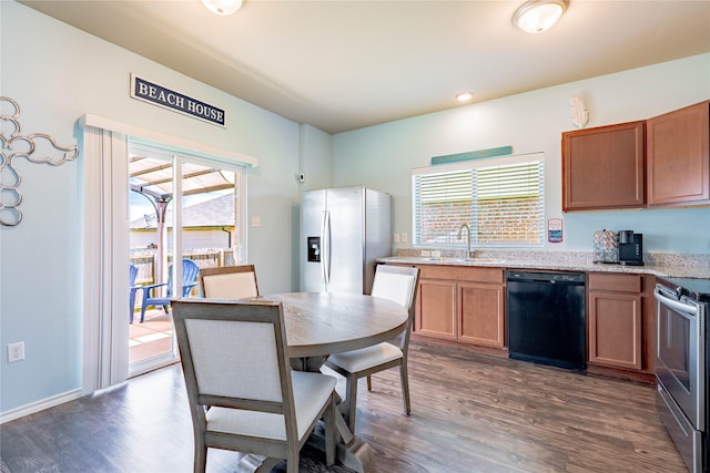306 Breaux Ln, Mabank, TX 75147 - kitchen featuring appliances with stainless steel finishes, a sink, dark wood-type flooring, brown cabinets, and light stone countertops