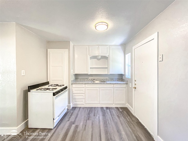 2234 Meander St, Abilene, TX 79602 - kitchen featuring white gas range oven, wood finished floors, white cabinets, baseboards, and light countertops