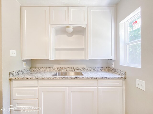 2234 Meander St, Abilene, TX 79602 - kitchen with white cabinets, open shelves, light stone counters, and a sink