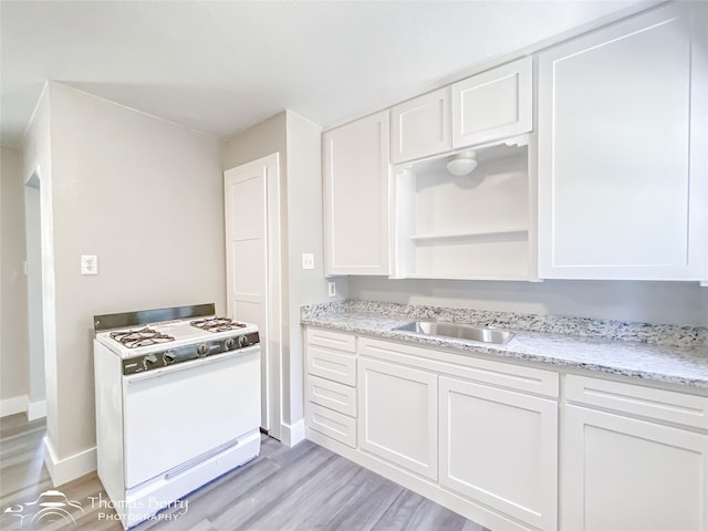 2234 Meander St, Abilene, TX 79602 - kitchen with white gas stove, a sink, light wood-style floors, and baseboards