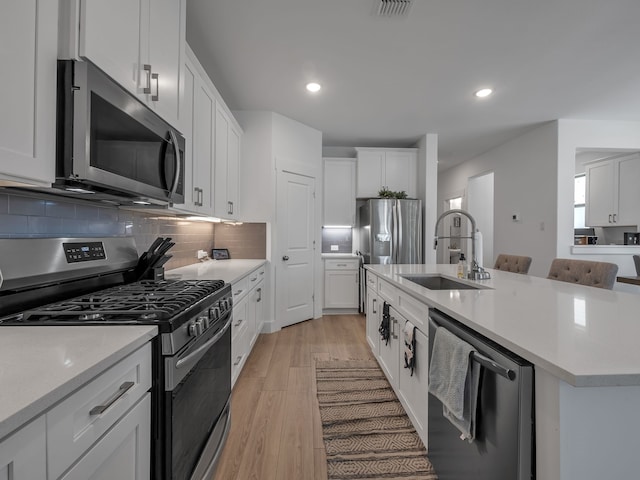 1409 Silver Marten Trl, Arlington, TX 76005 - kitchen featuring stainless steel appliances, a sink, light countertops, a center island with sink, and recessed lighting