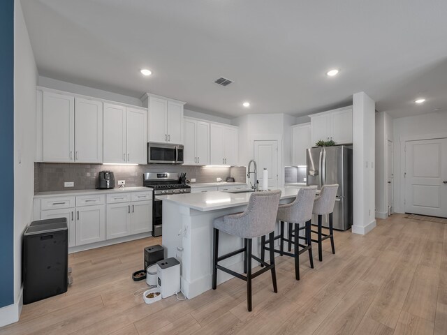1409 Silver Marten Trl, Arlington, TX 76005 - kitchen featuring stainless steel appliances, a sink, white cabinetry, backsplash, and a breakfast bar area