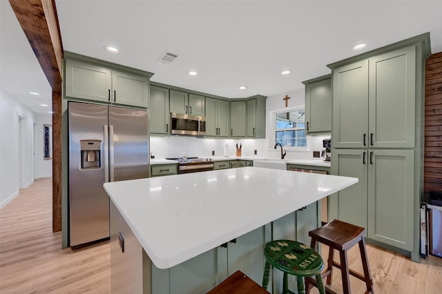 4491 Dugan Chapel Rd, Bells, TX 75414 - kitchen with green cabinets, appliances with stainless steel finishes, light wood finished floors, a center island, and light countertops