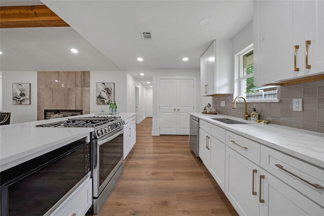 2520 Delmar Dr, Plano, TX 75075 - kitchen with stainless steel appliances, white cabinetry, tasteful backsplash, light stone countertops, and recessed lighting