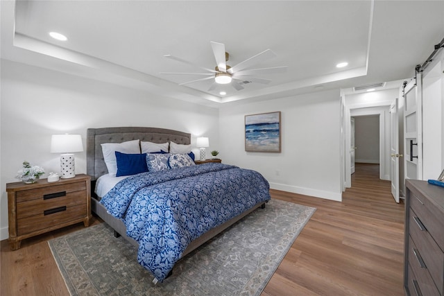 2520 Delmar Dr, Plano, TX 75075 - bedroom with a tray ceiling, a barn door, light wood-type flooring, recessed lighting, and ceiling fan
